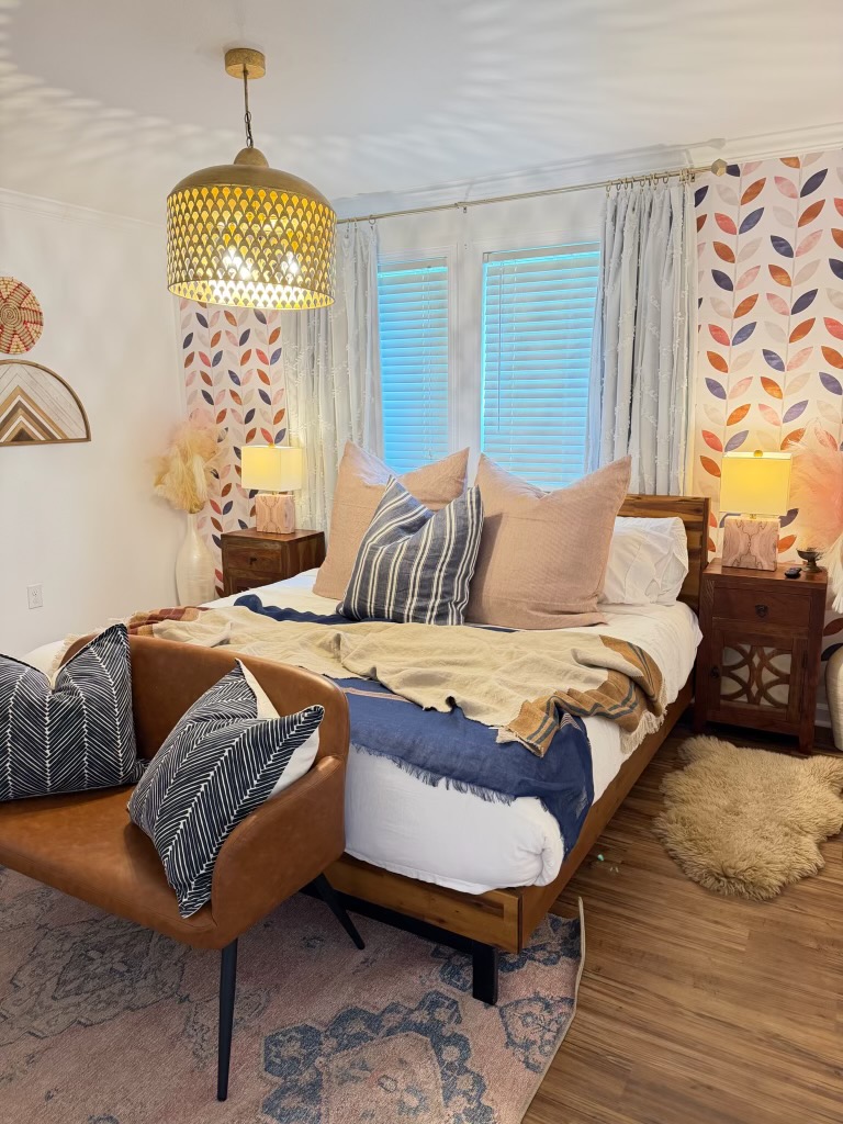 Poplar Place bedroom with a brass pendant, leather reading chair, and soft Hill Country light through the curtains.