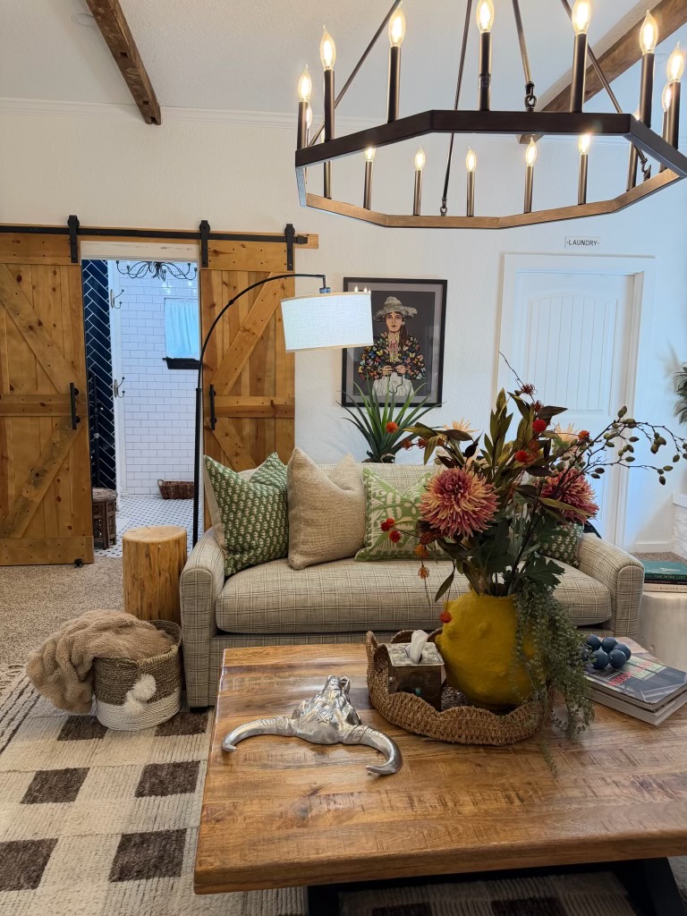 Poplar Place living room with a wagon-wheel chandelier, a checked sofa, and sliding barn doors.